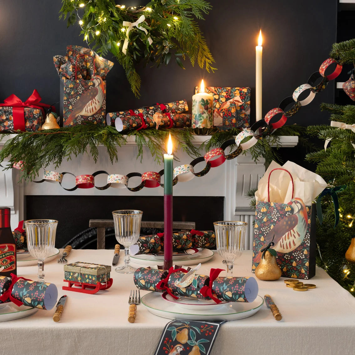 Decorative Christmas table setting with crackers, candles, and gift bags.