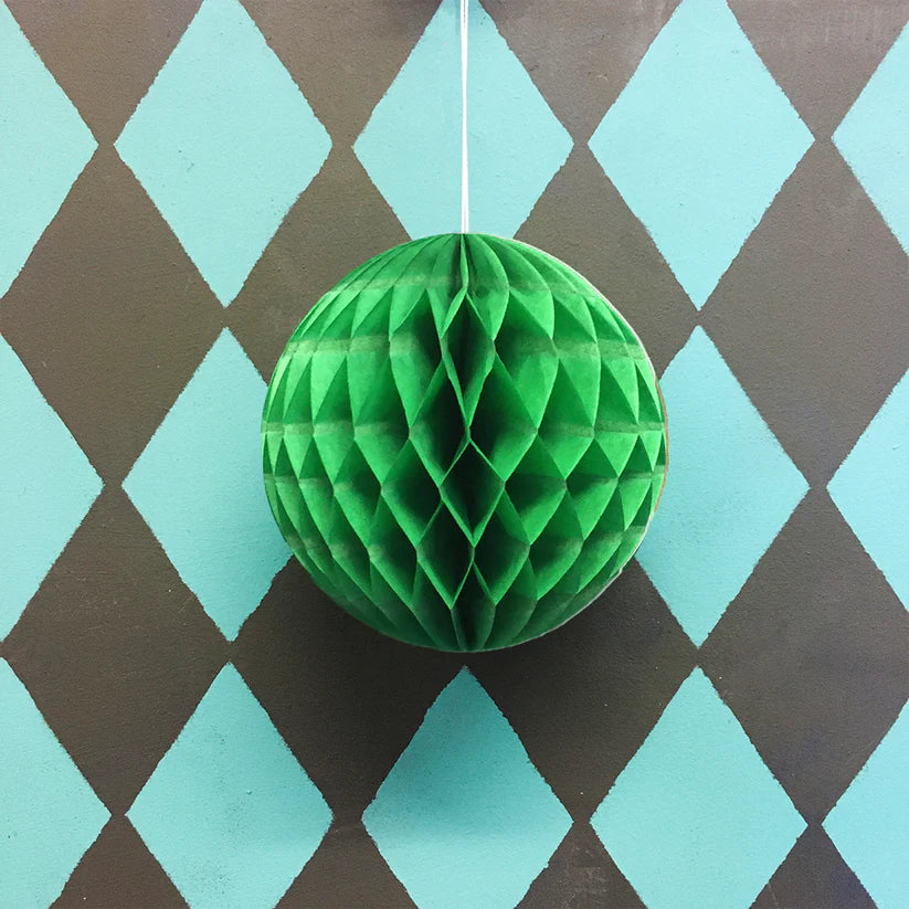 Green honeycomb paper ball hanging against a teal and brown diamond patterned background.