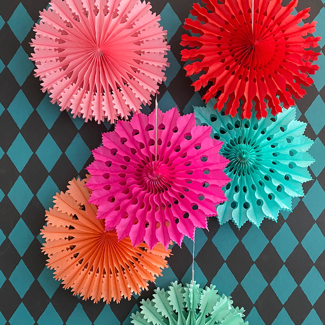 Collection of colorful paper fan decorations. Various sizes and bright colors including pink, red, orange, and teal.