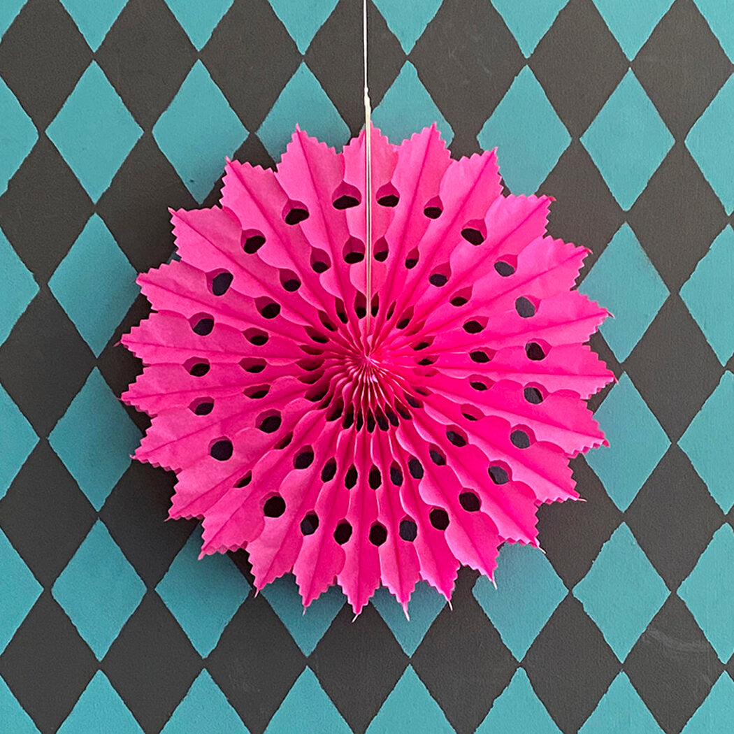 Hot pink paper fan decoration with cut-out detailing.