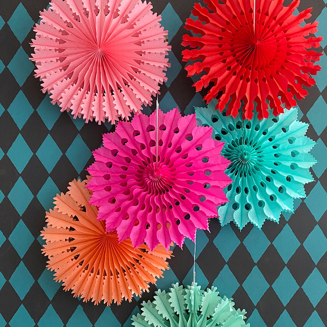 Collection of colorful paper fan decorations; pink, red, teal, and orange. Intricate cut-out designs.