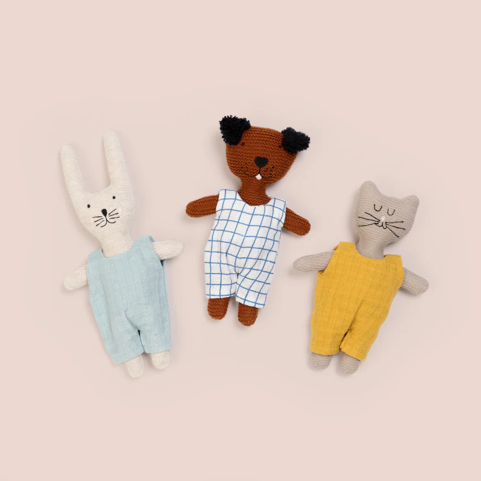 Three crocheted stuffed animals wearing overalls: a rabbit in light blue, a dog in blue gingham, and a cat in mustard yellow.