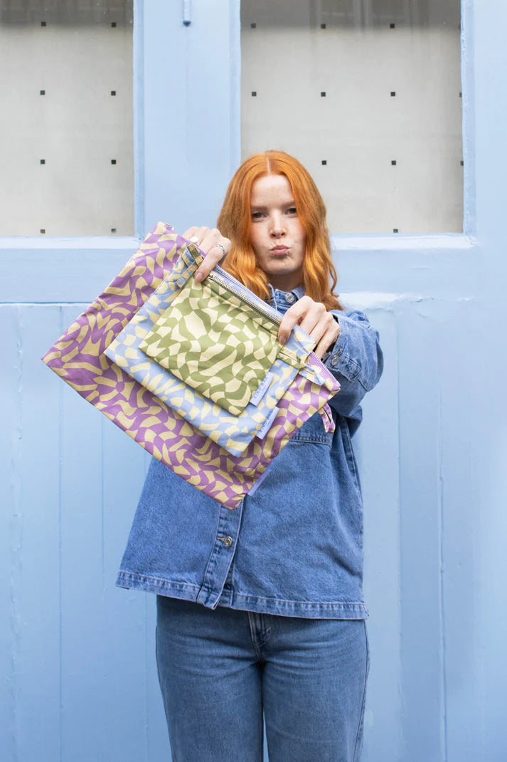 Three reusable zipper pouches in lavender, light blue, and olive green abstract swirl patterns.