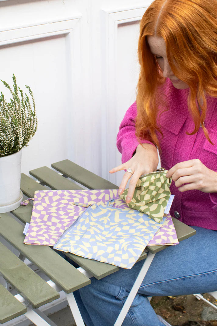 Three zippered pouches in pastel purple, light blue, and olive green.  Each features an abstract geometric pattern.