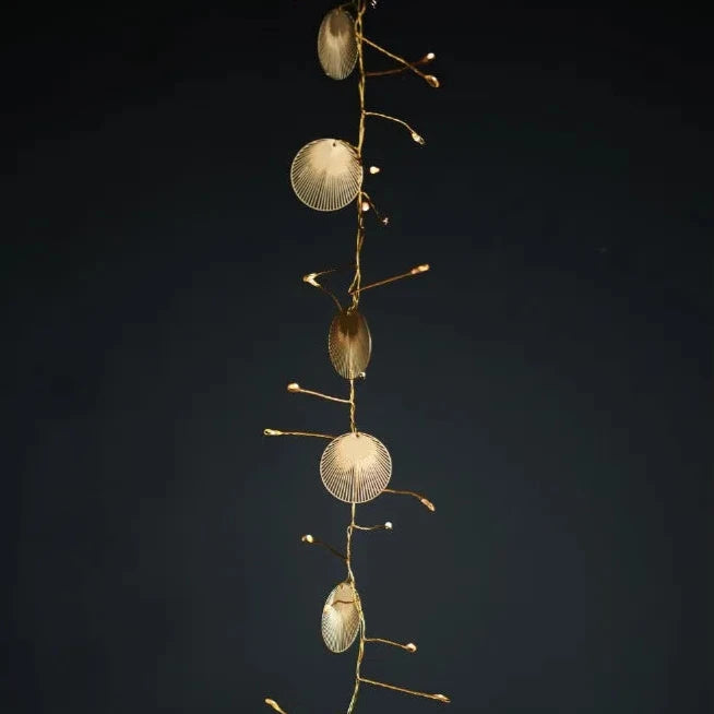 Gold metal shell-shaped and oval decorative lights strung on thin wire.