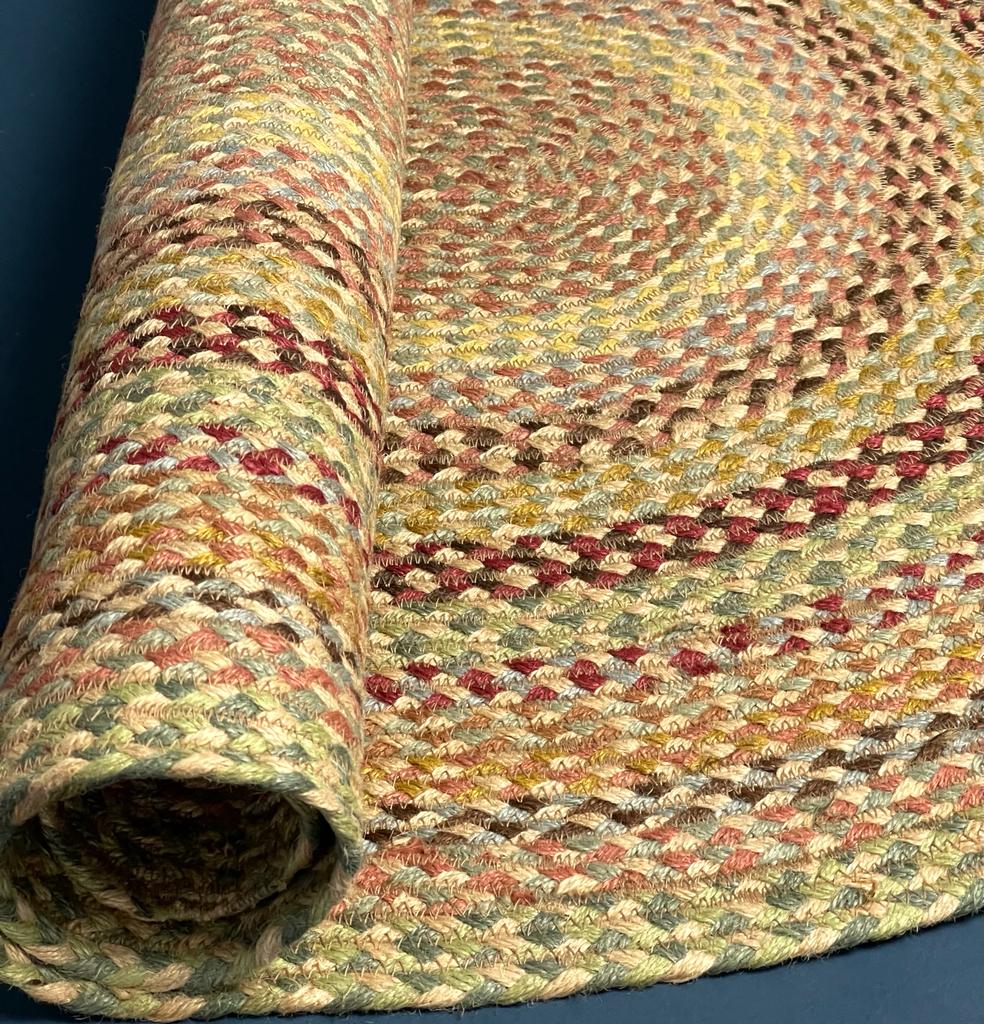 Rolled-up braided jute rug in earth tones; featuring a multicolored, concentric circular pattern.