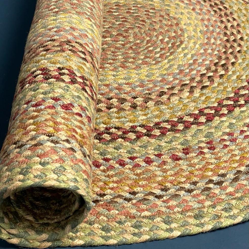 Rolled braided rug in muted autumnal colors; beige, brown, red, and green tones.