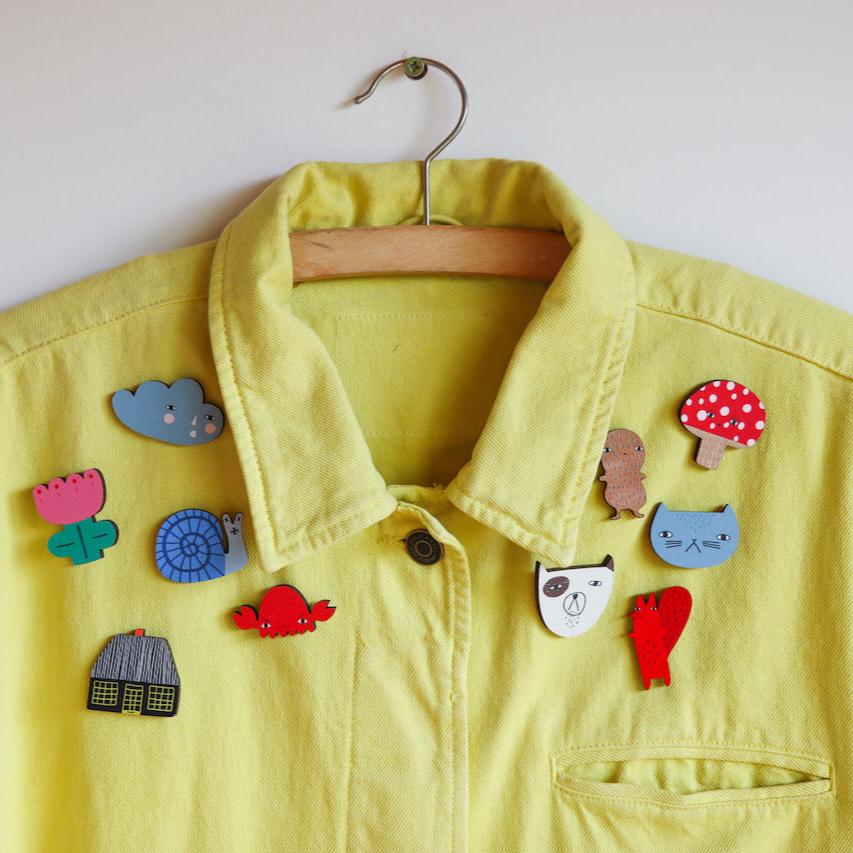 Yellow jacket by Donna Wilson, adorned with colorful wooden pins including flowers and animals.