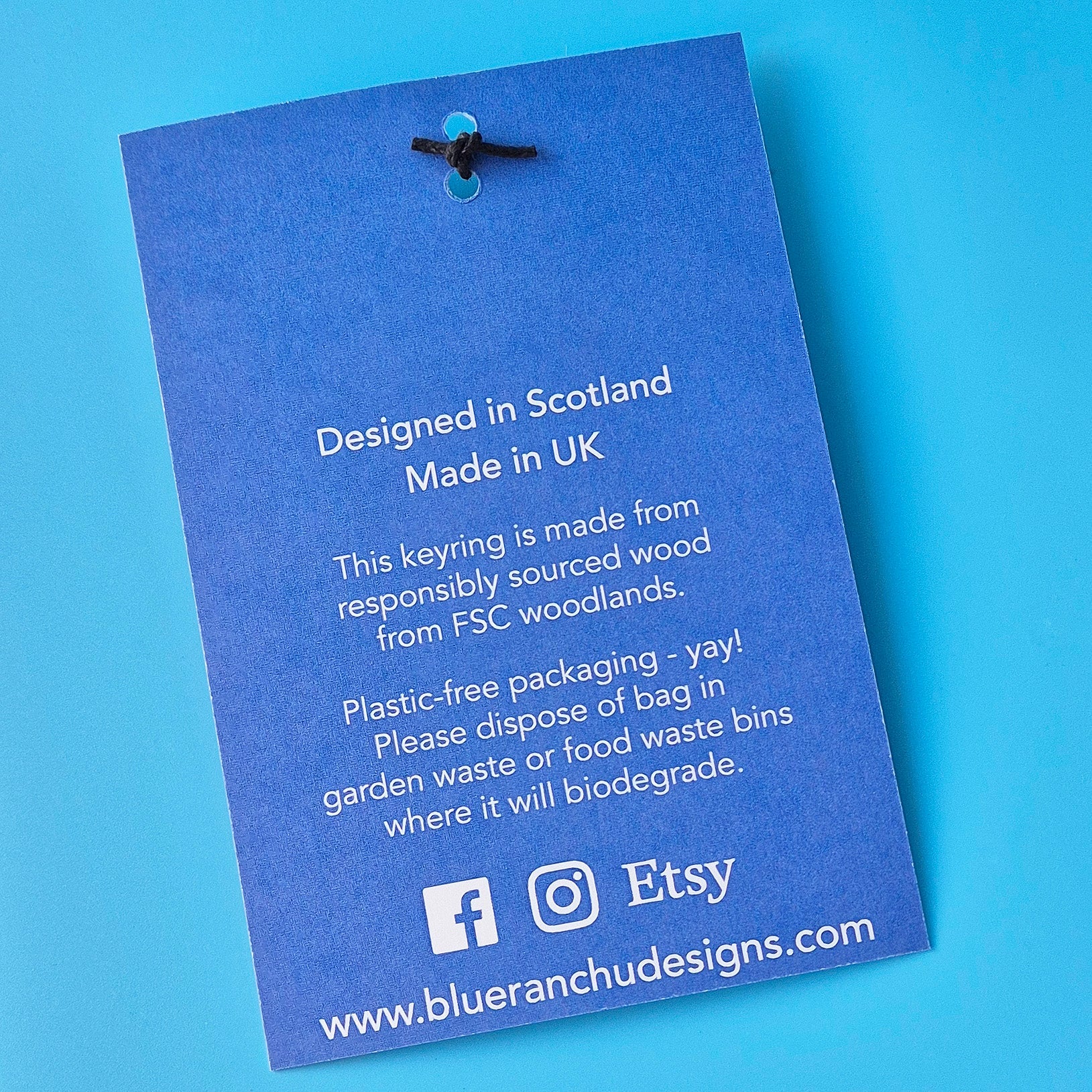 Blue keyring label with text about origin and sustainability on a blue background