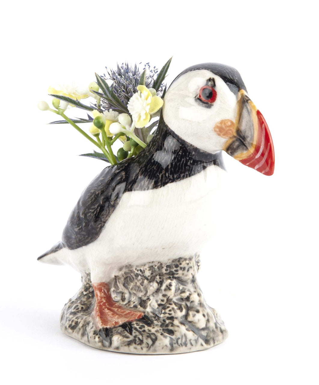 Ceramic puffin planter with small bouquet of flowers.  The puffin is realistically painted, perched on a rocky base.