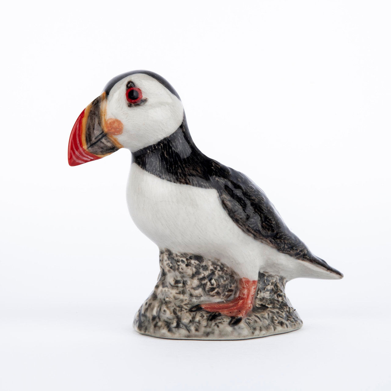 Ceramic puffin figurine, perched on a textured base, detailed with black, white, and red markings.