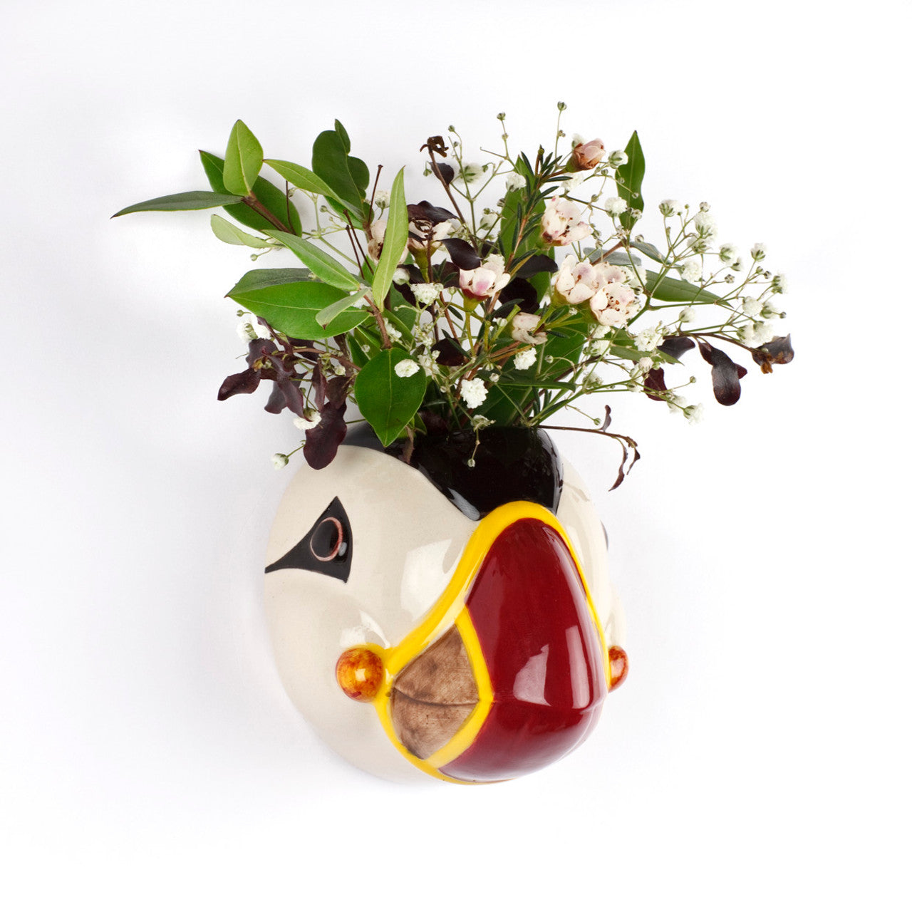 Ceramic puffin-shaped planter with small white and pink flowers.
