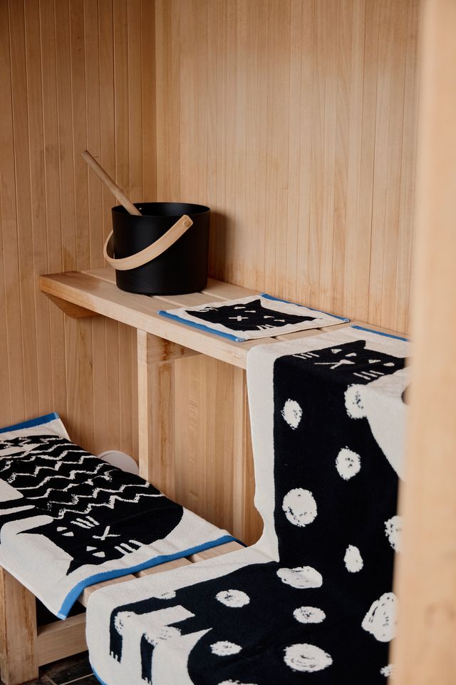 Wooden bench with black and white patterned blanket in a wooden room.