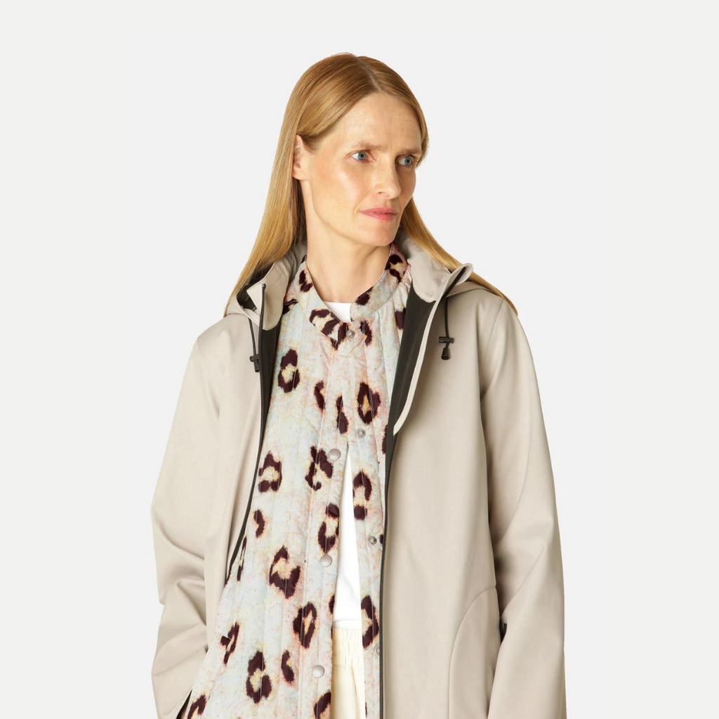 Beige hooded raincoat with a leopard print shirt underneath, worn by a blonde woman.