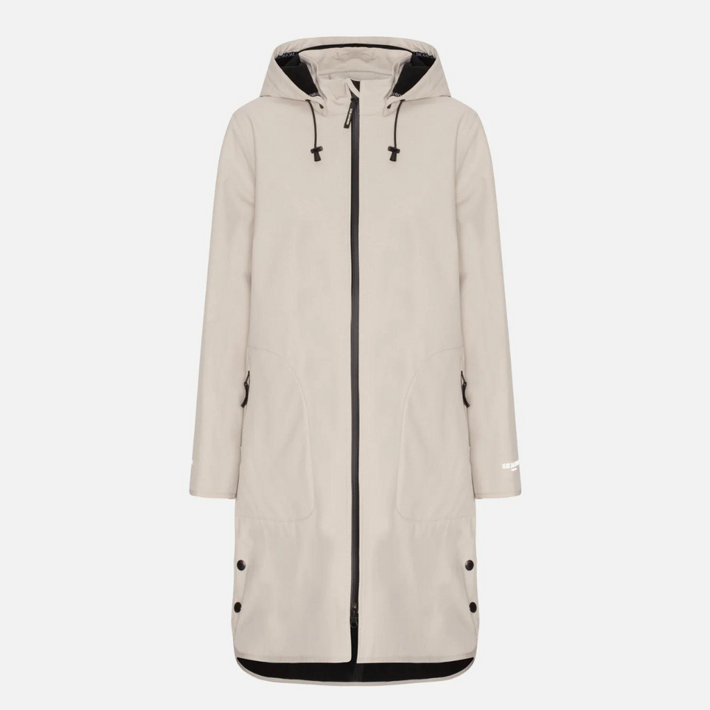 Beige hooded raincoat with zipper closure, welt pockets, and snap buttons at the hem. Features a minimalist design and subtle