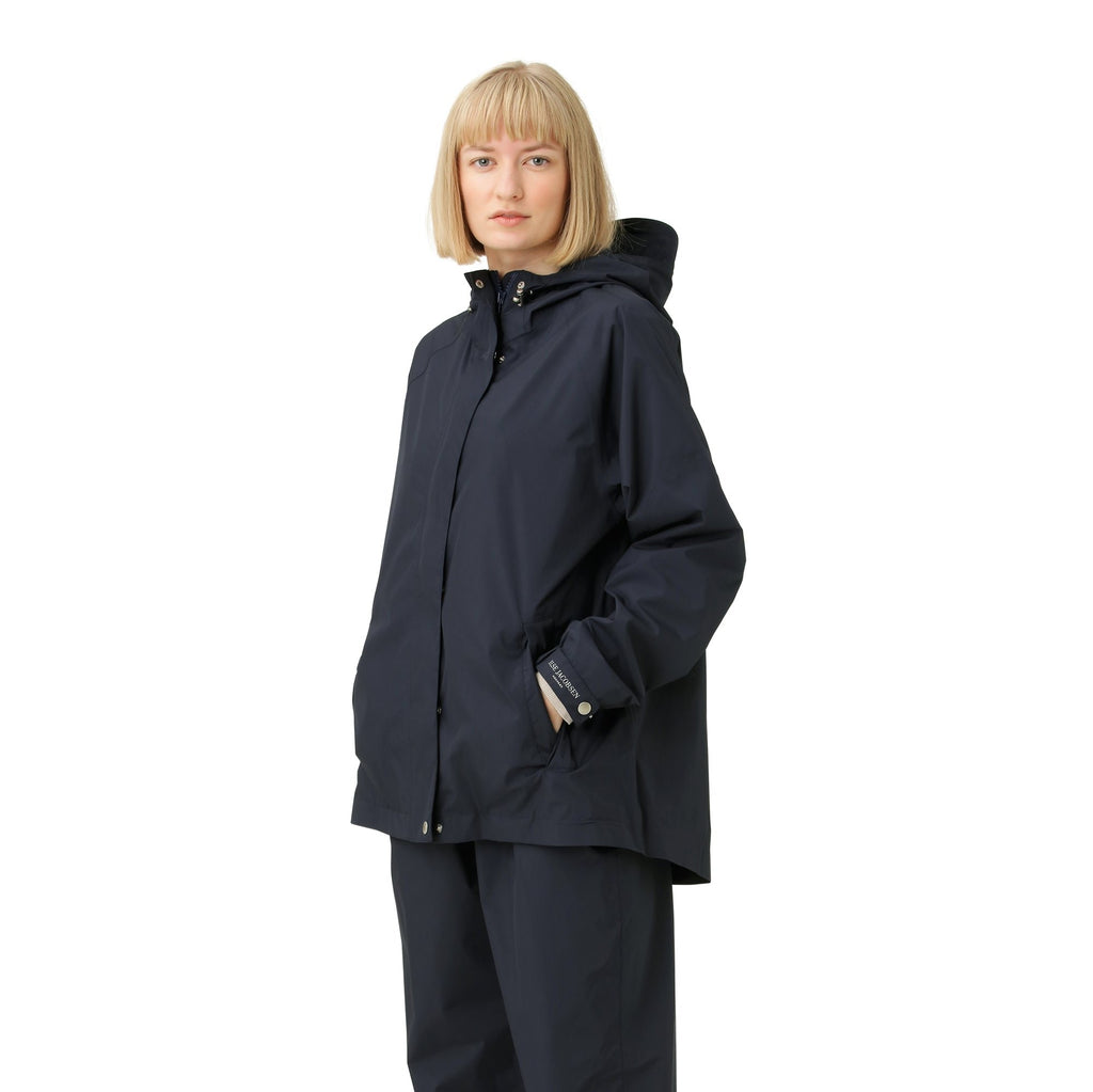 Woman in navy blue Usd Jacobsen hooded jacket and matching pants, hands in pockets, against white background.