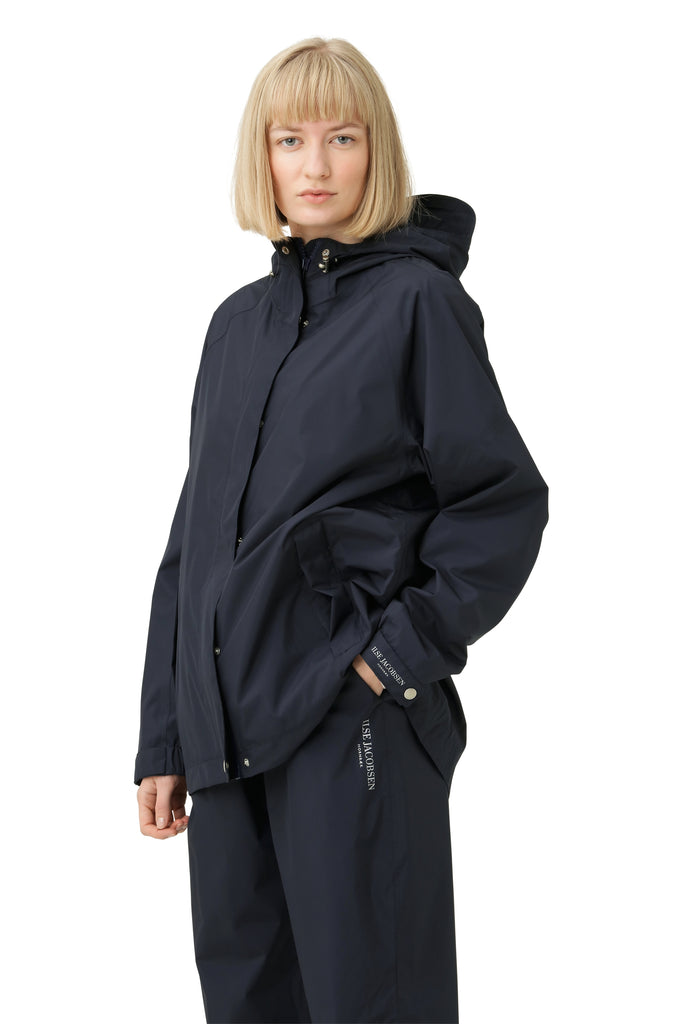 Woman in navy Ilse Jacobsen Hornbæk hooded jacket and trousers. Smooth, matte fabric. Subtle branding.