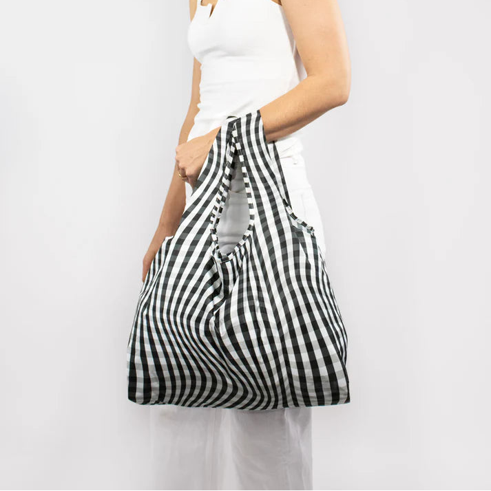 Black and white gingham reusable shopping bag.  The bag is folded and held by a person.