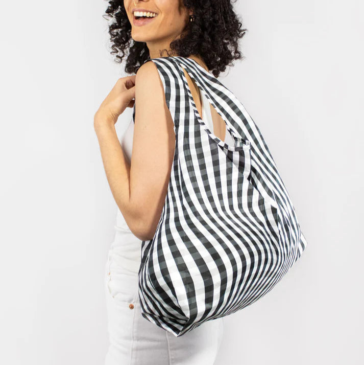 Black and white gingham reusable shopping bag with wavy stripes, worn over a shoulder.