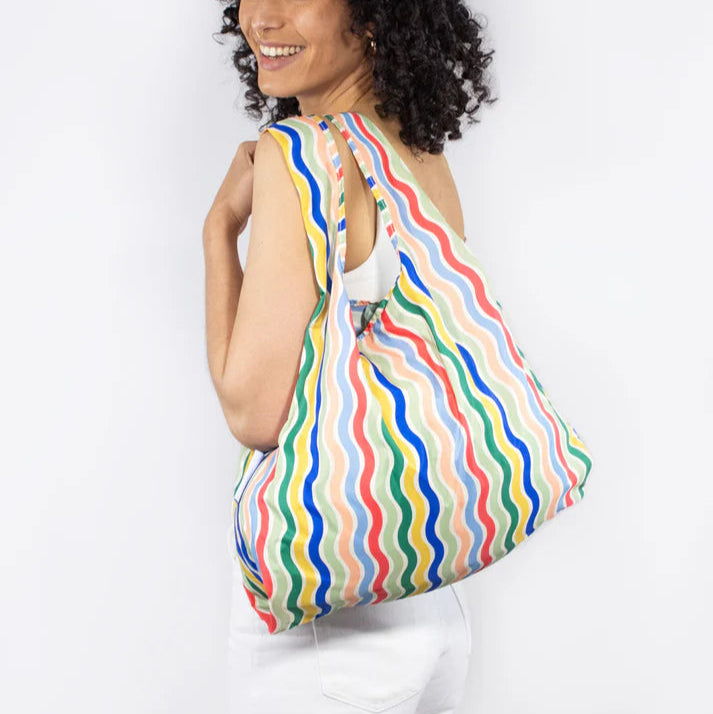 Reusable shopping bag with multicolored wavy stripes.