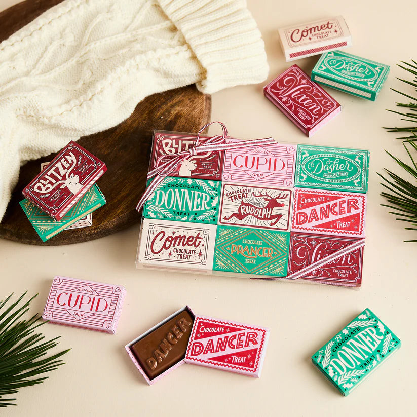 Assortment of miniature chocolate bars in matchbox-style packaging; each box features a reindeer's name and festive design.