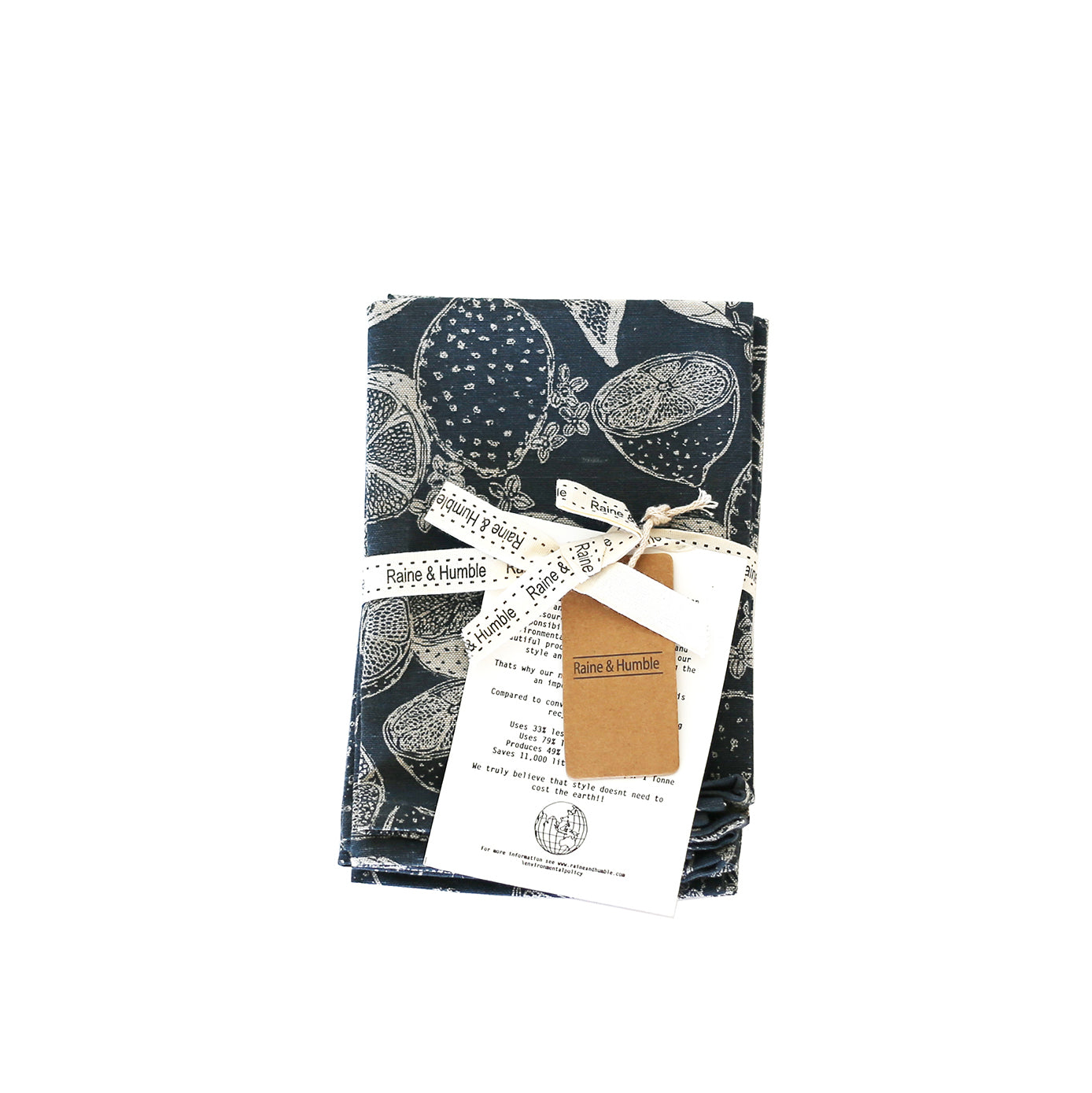Dark blue tea towel, folded, featuring a white citrus fruit print.  Packaged with a brand tag.