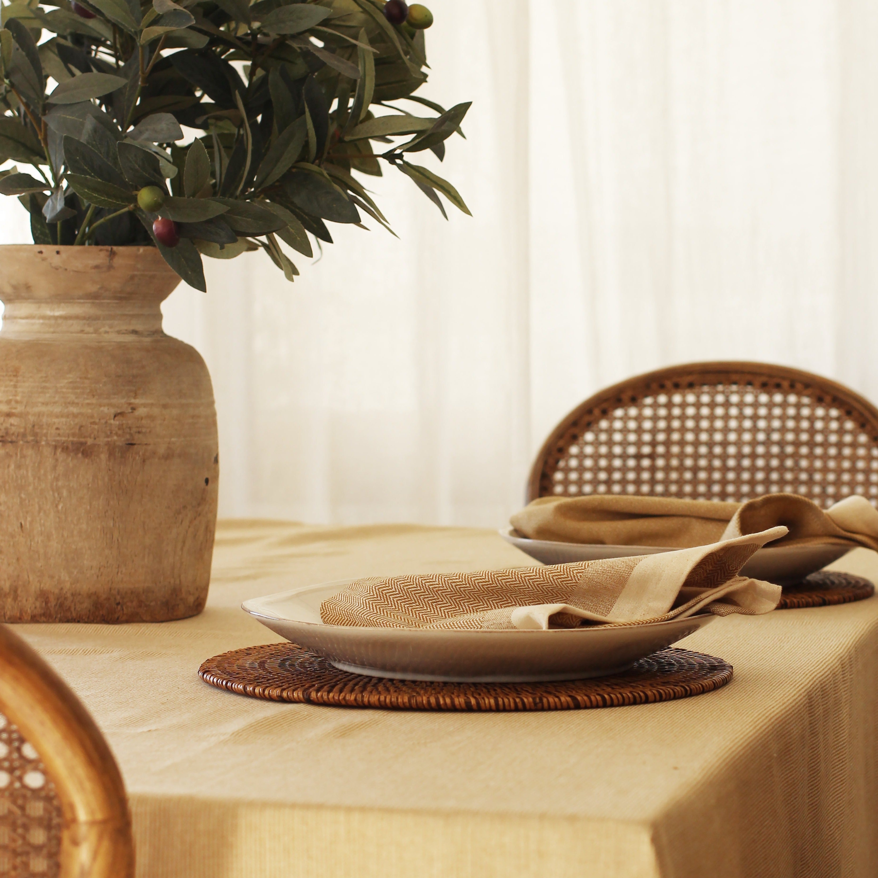 Beige linen placemats and napkins with a herringbone pattern on a light beige tablecloth.