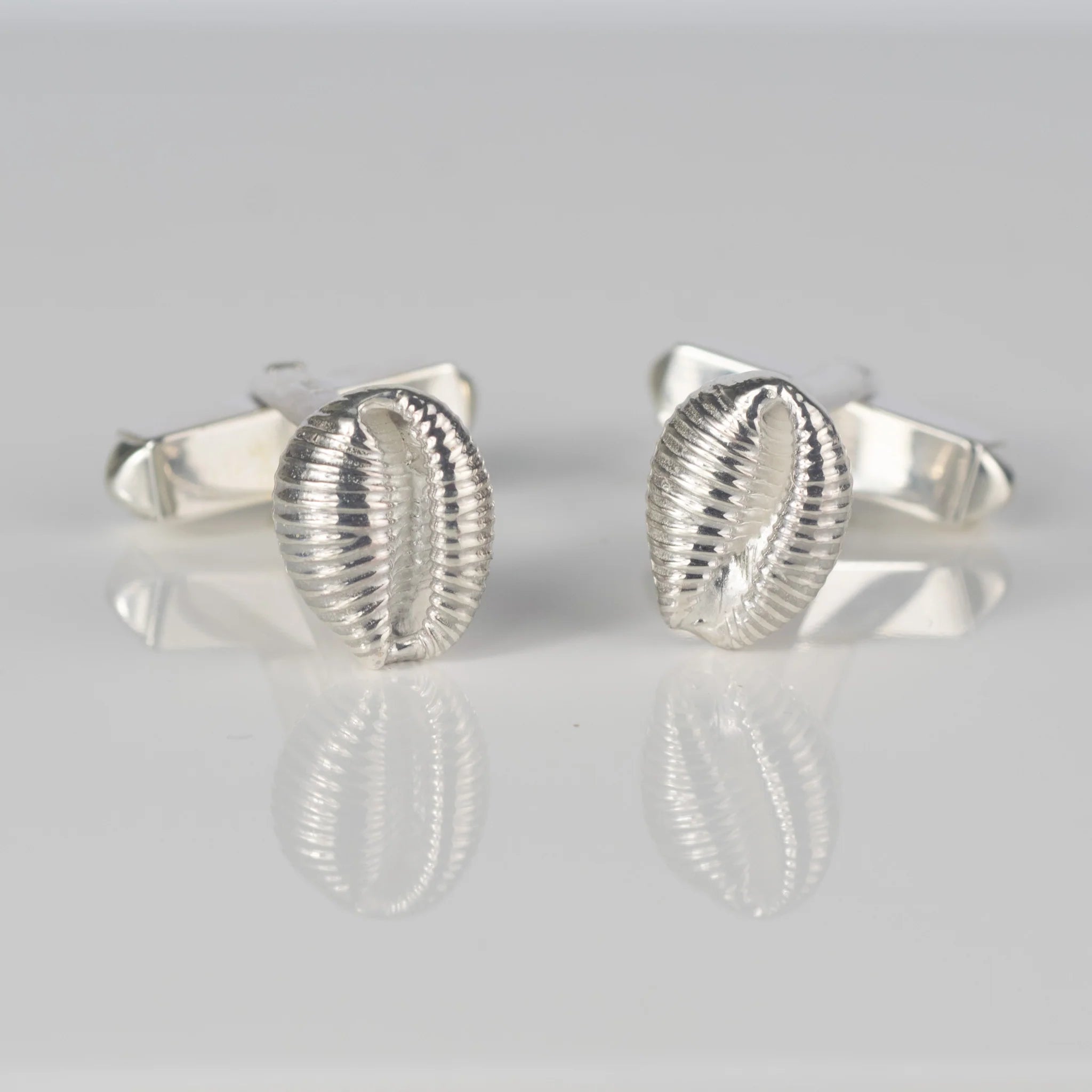 Pair of silver cufflinks; each features a detailed, ribbed seashell design.