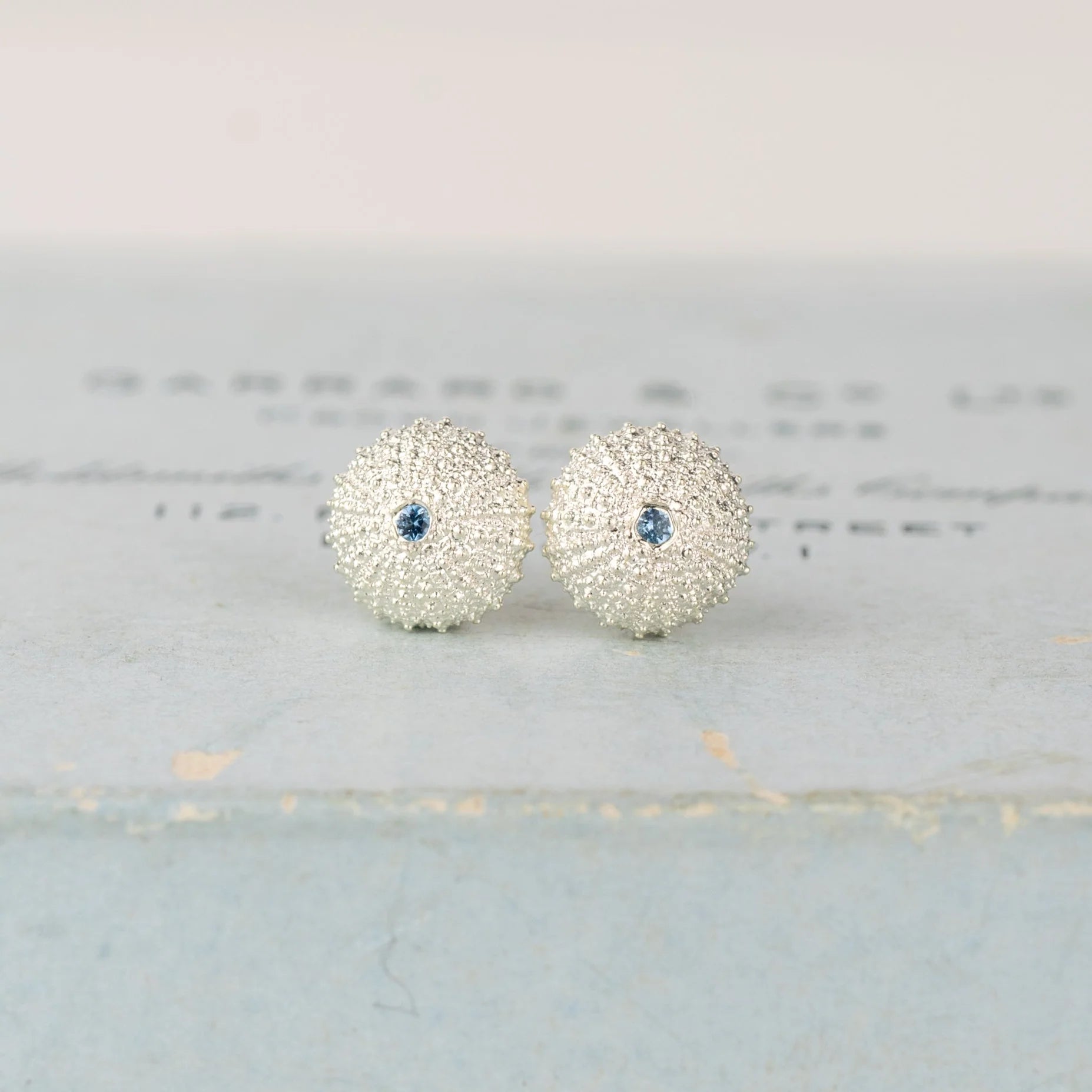 Silver earrings with blue gemstones on a light gray background
