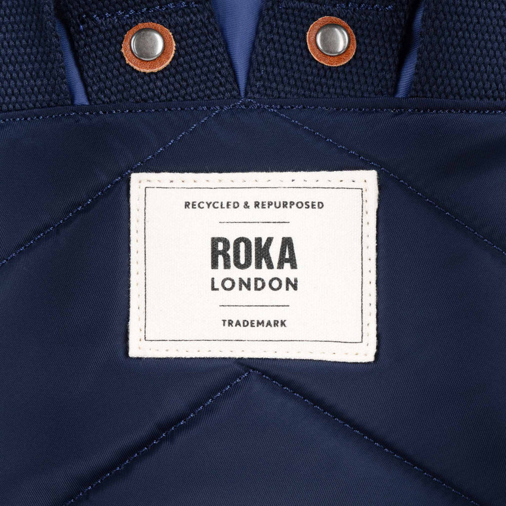 Navy blue fabric with a Roka London label on a close-up of clothing.
