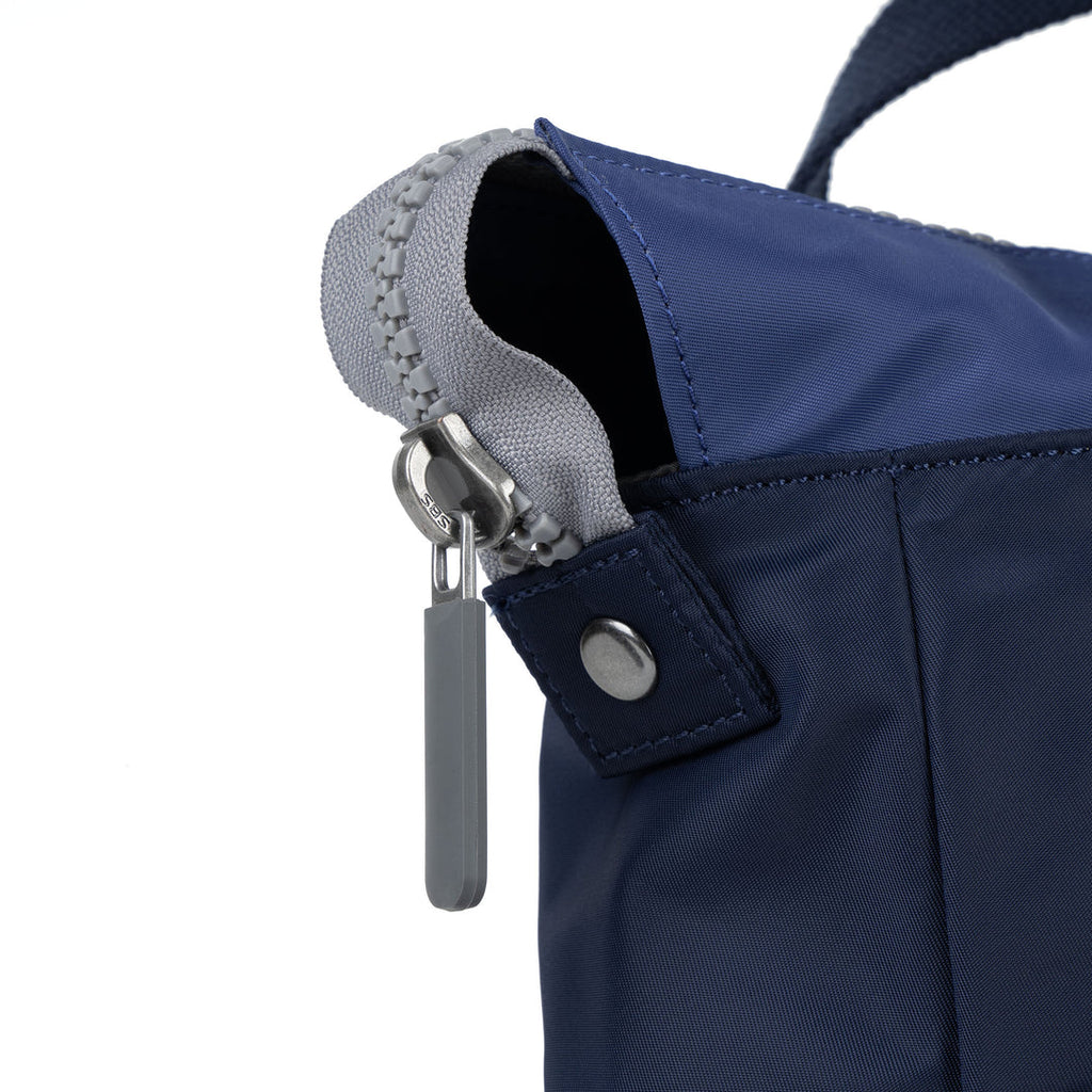 Close-up of a navy blue bag with a gray zipper on a white background