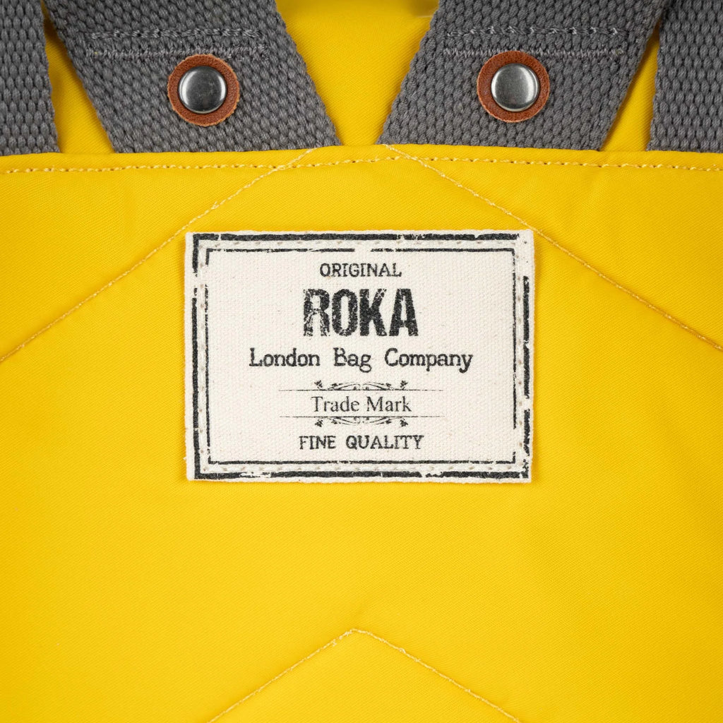 Close-up of a yellow bag's label, reading "Original ROKA London Bag Company, Trade Mark, Fine Quality".