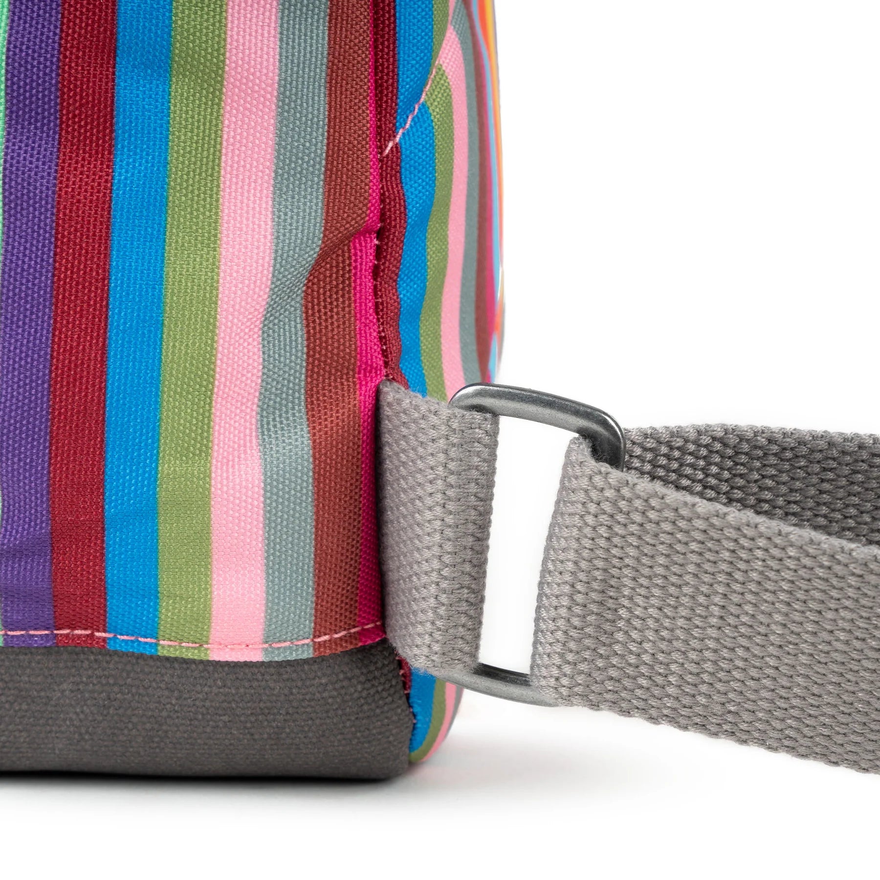 Multicolored striped fabric bag with gray canvas bottom and gray straps; metal hardware accents the strap attachment.