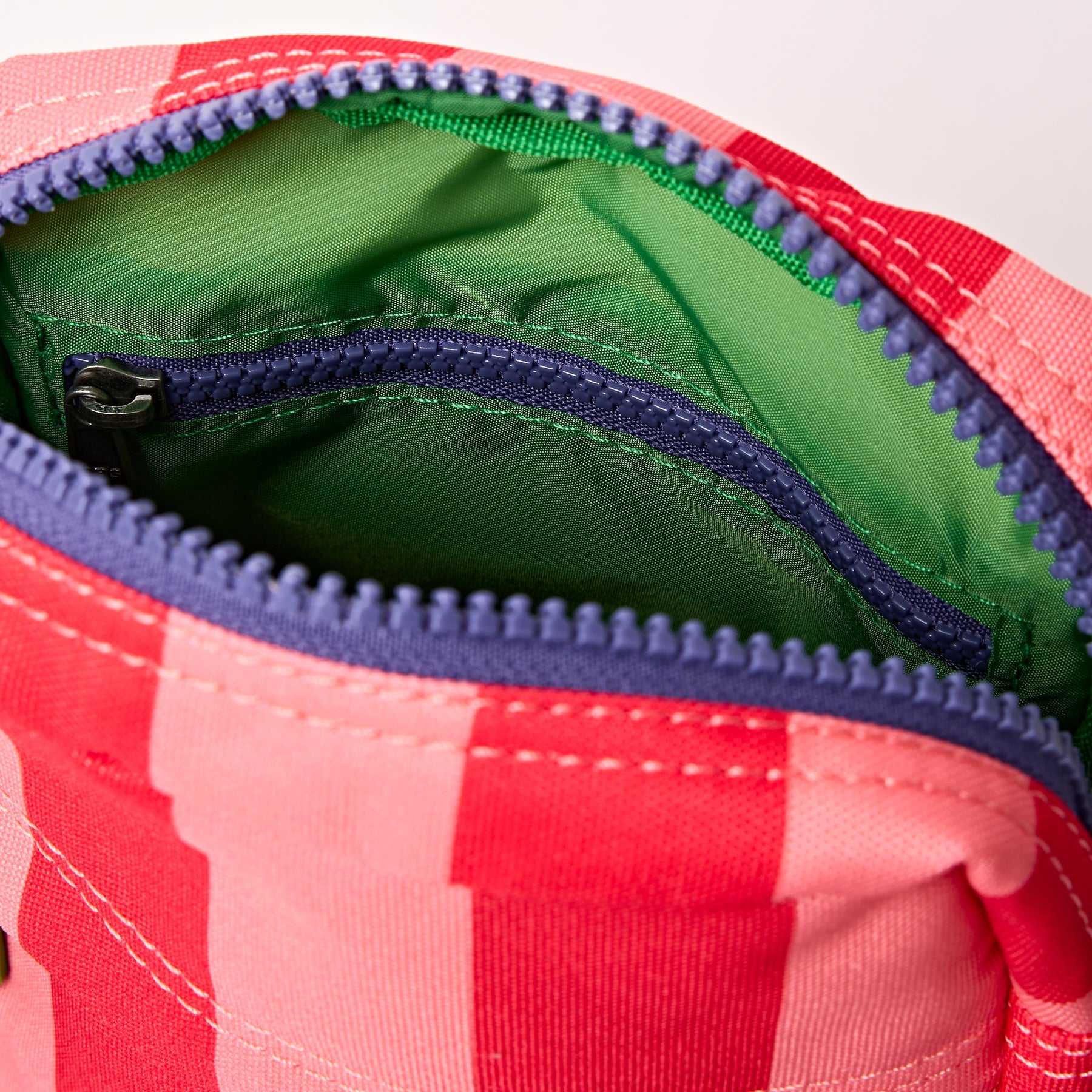Close-up of a red and green checkered bag with a zipper.