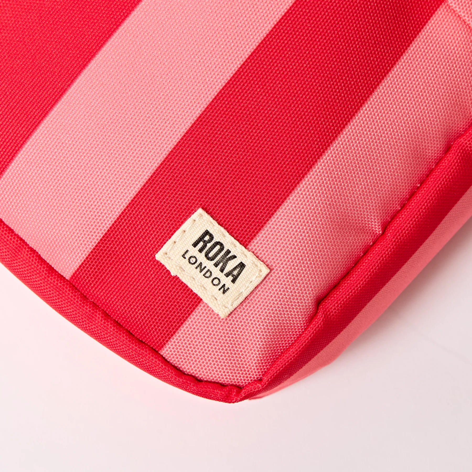 Red and pink striped pouch with Roka London label on a white background