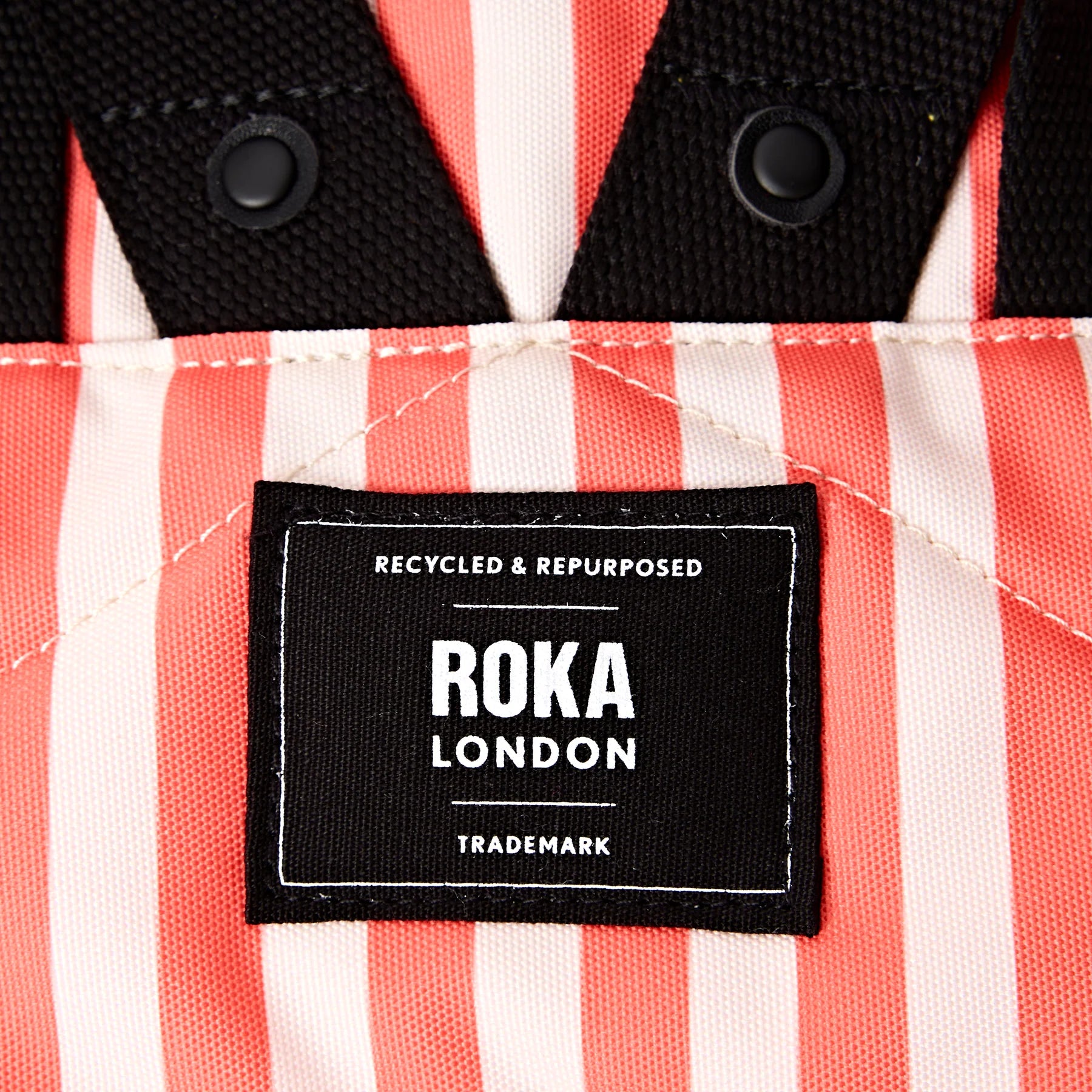Close-up of a Roka London label on a red and white striped fabric background
