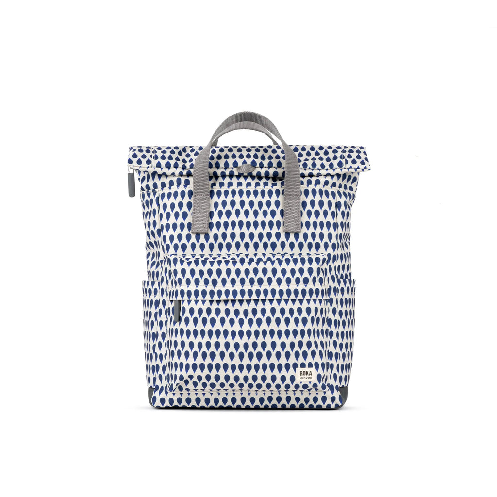 White and navy blue ROKA backpack with a drop pattern and front pocket, featuring gray straps.