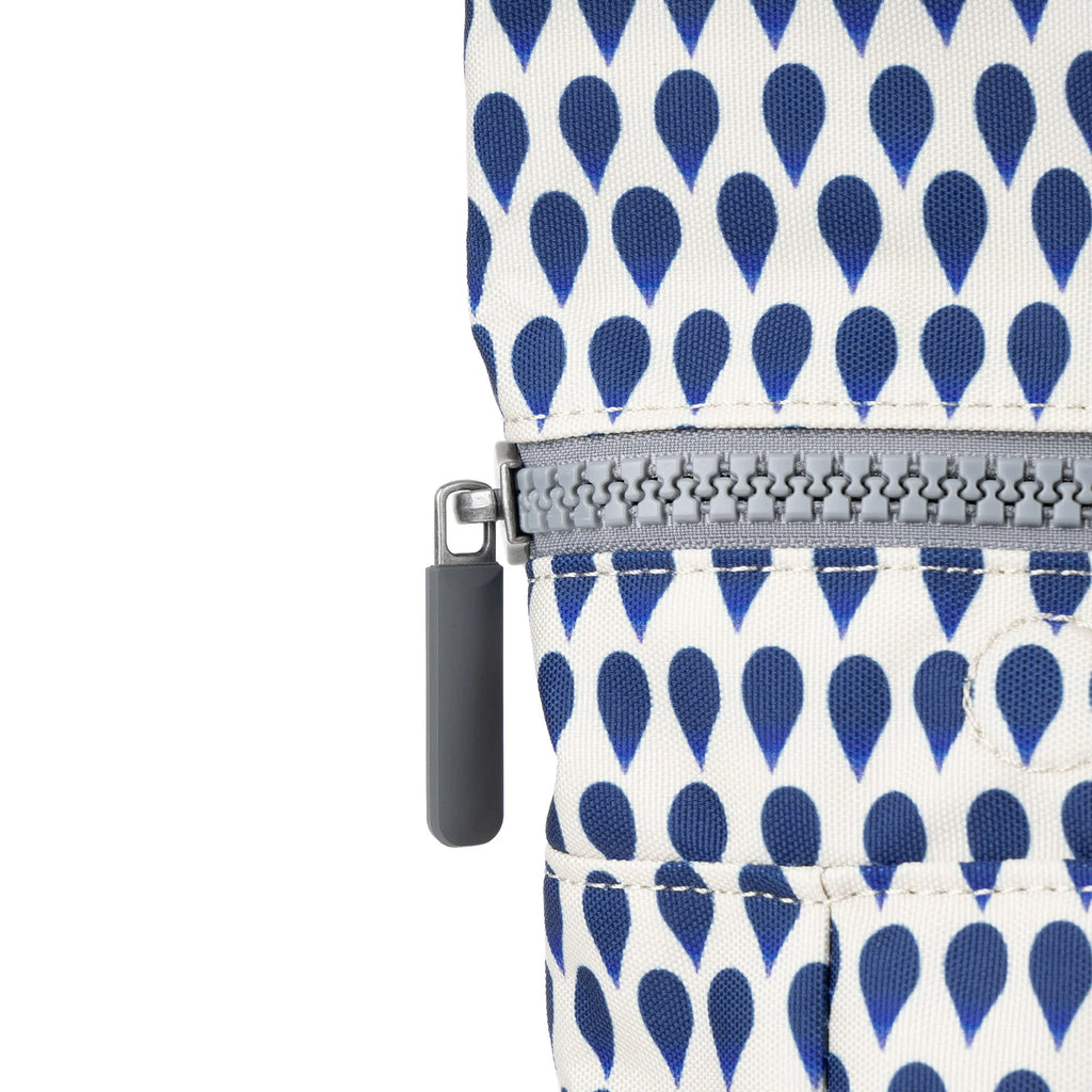 ROKA bag detail featuring a zipper with a gray pull tab on a patterned fabric of blue teardrop shapes.