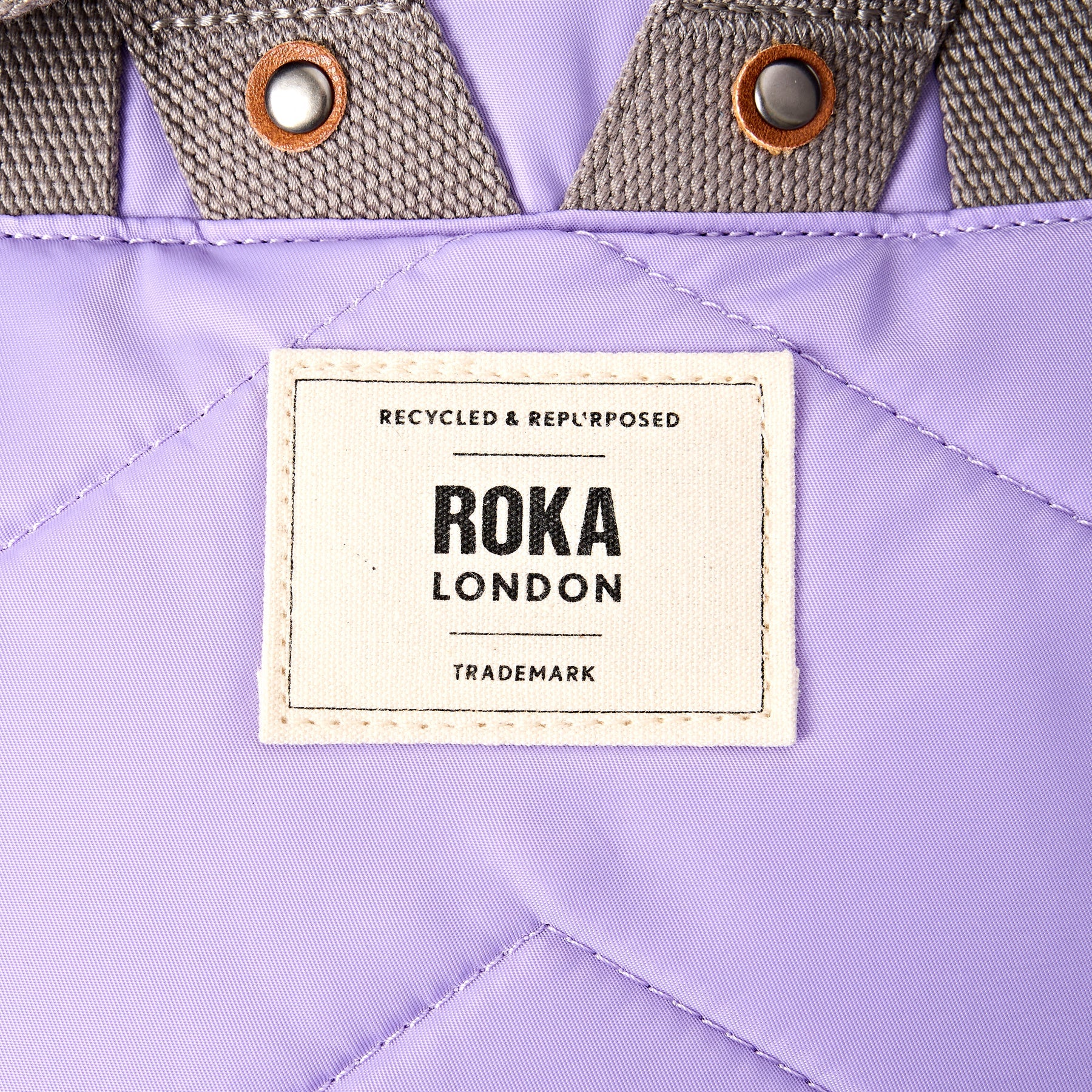Roka London label on a purple bag with brown stitching
