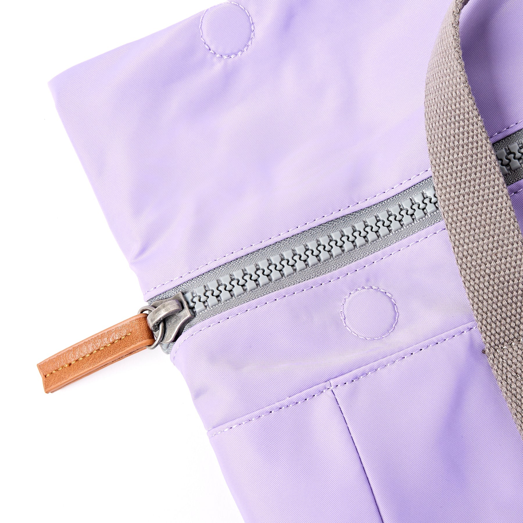 Close-up of a lavender bag with a zipper and brown handle on a white background