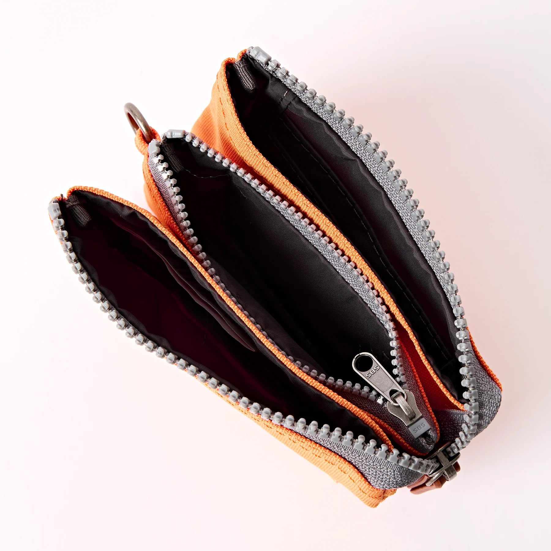 Open orange and gray zippered pouch on a light pink background