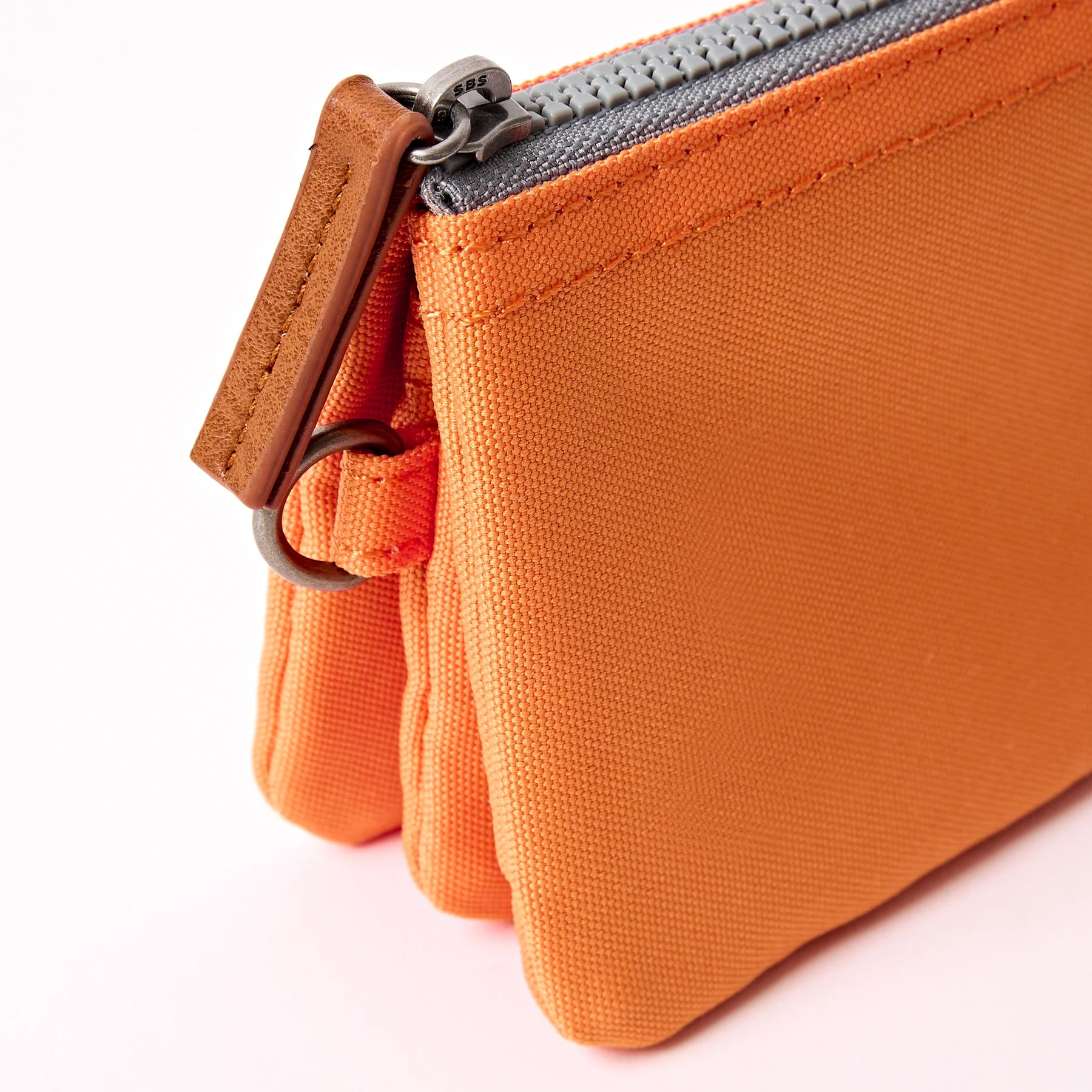 Close-up of an orange fabric pouch with a zipper on a white background