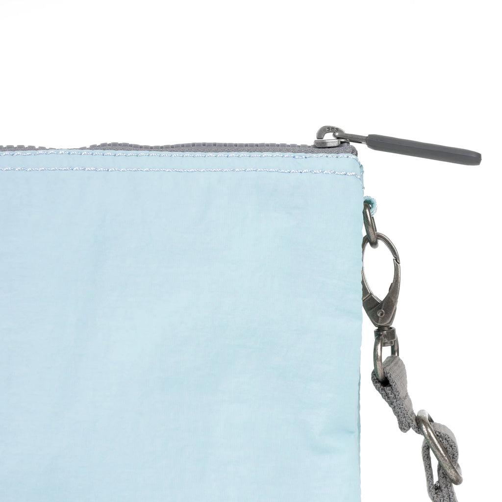 Light blue ROKA bag corner with zipper and gray strap attached, featuring a metal clip.