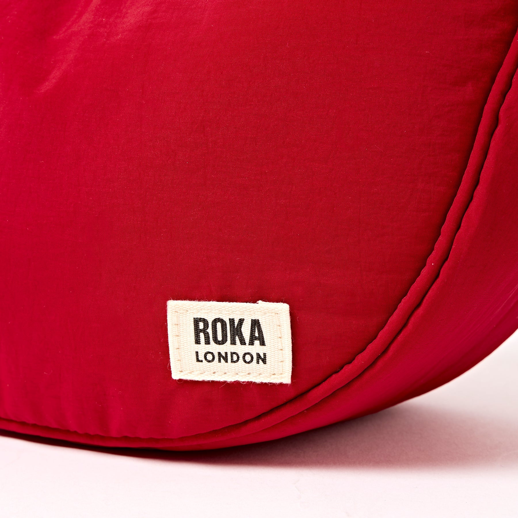 Red bag with a Roka London label on a white background