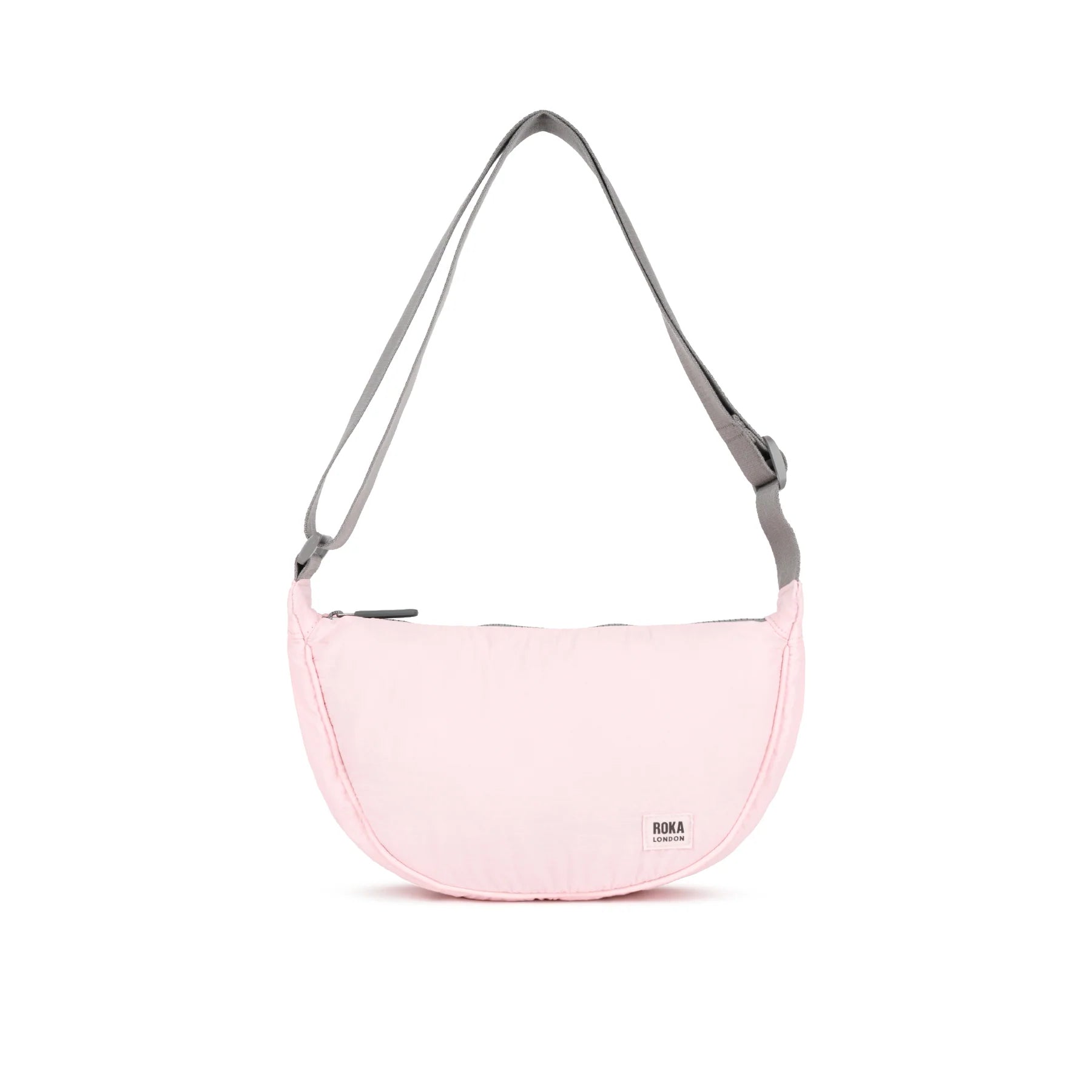 Pink ROKA bag with a gray adjustable strap, featuring a simple design and zipper closure.