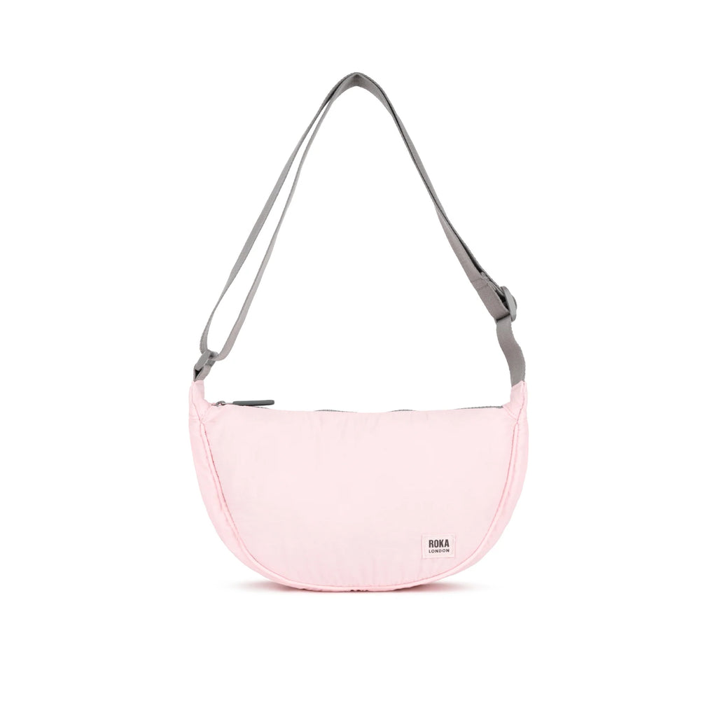 Pink ROKA bag with a gray adjustable strap, featuring a simple design and zipper closure.