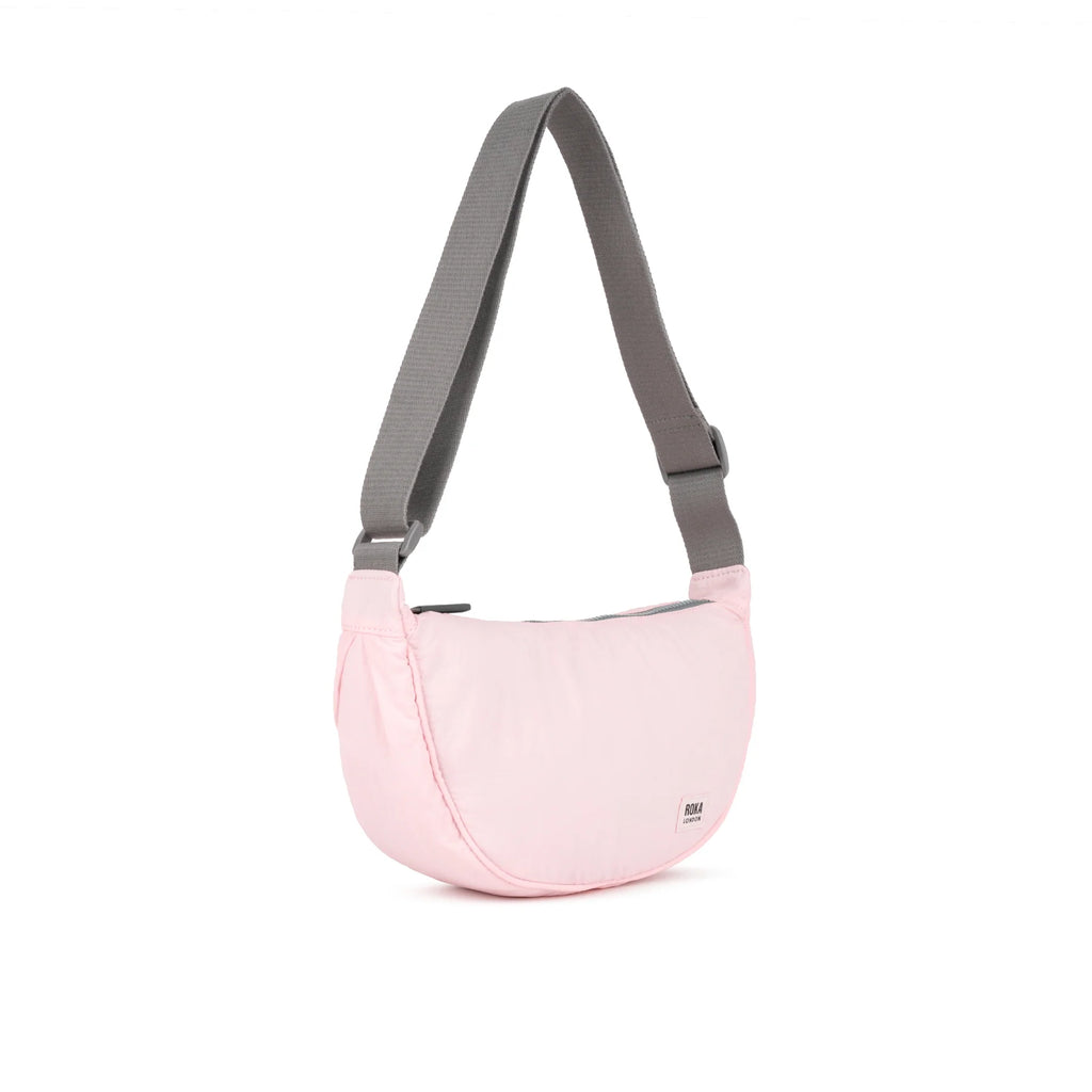 ROKA stylish pink crossbody bag with a gray strap, featuring a sleek and minimalist design.