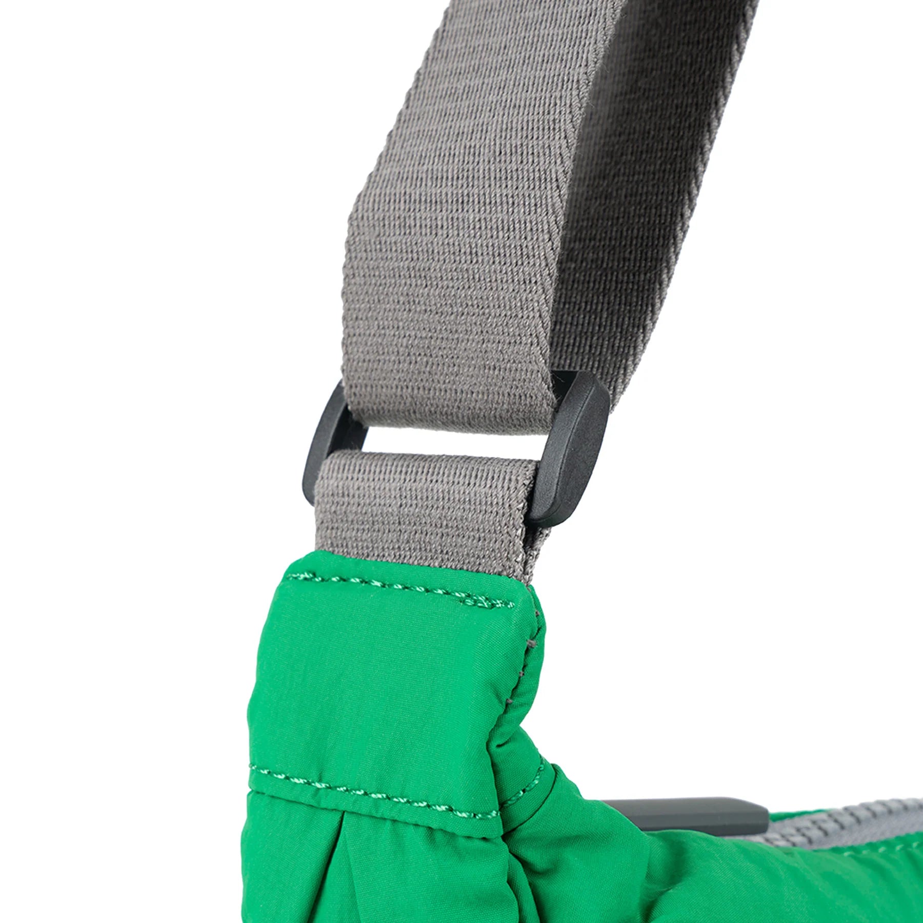 Close-up of a bright green bag's shoulder strap, showing a grey fabric strap with black plastic slider adjusters.