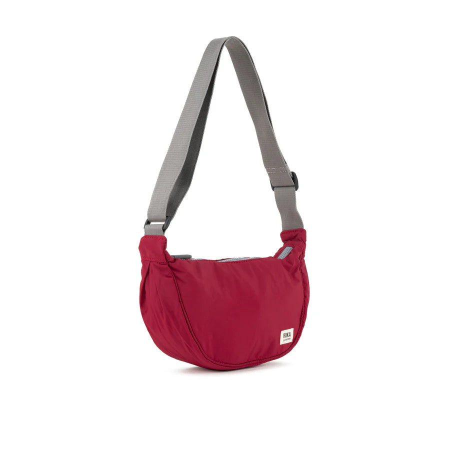 Red crescent-shaped crossbody bag with gray shoulder strap.