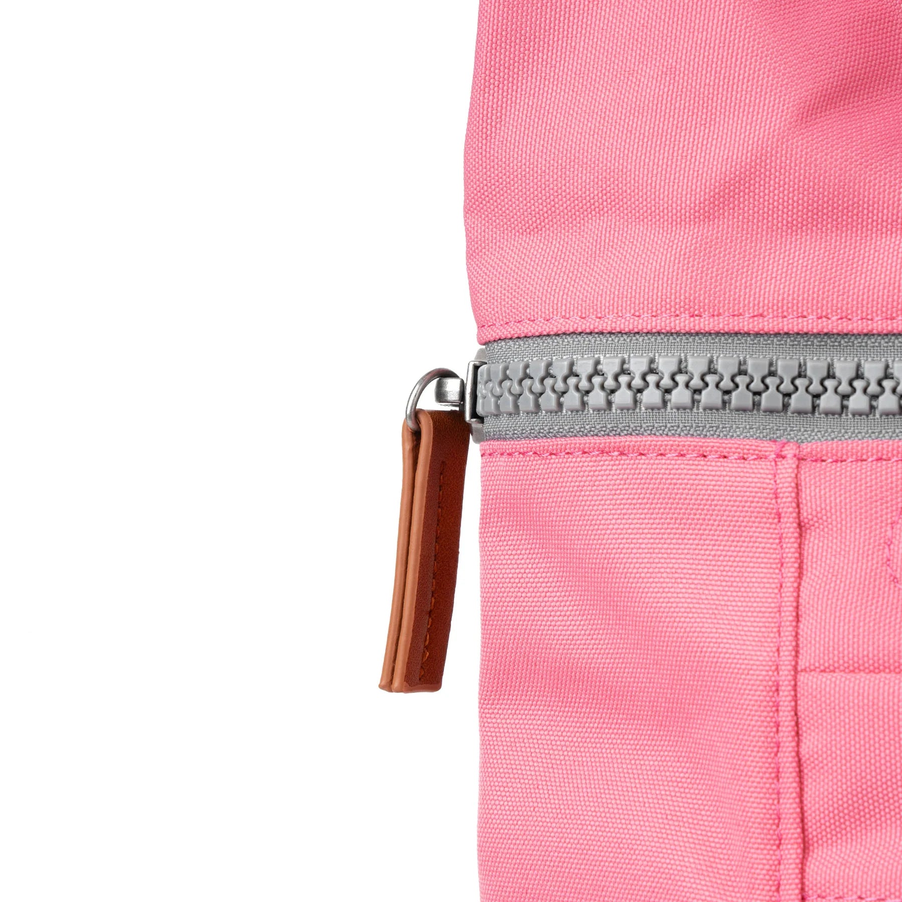 Close-up of a pink ROKA bag featuring a silver zipper and a brown leather pull tab.